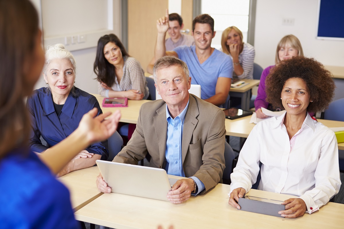 Adult students learning with their teacher in a bright classroom
